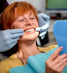 Woman in dental chair admiring her smile
