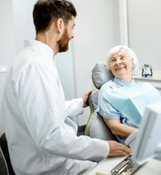 Senior woman smiling at dentist after receiving dentures in Jacksonville