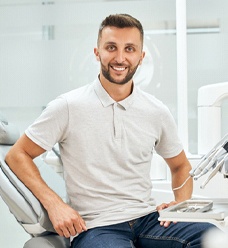 Man smiling while sitting up straight in dental chair