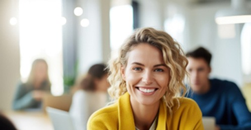 Woman in yellow jacket smiling at office
