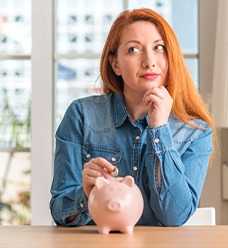 Woman putting a coin into a piggy bank