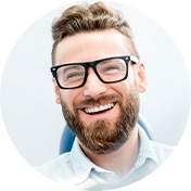 Man with glasses smiling in dental chair