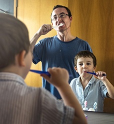 A father and son brushing their teeth together