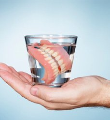 a person holding a cup of water with dentures