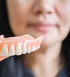 a woman holding a set of dentures