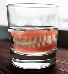 a pair of dentures in a glass cup of water