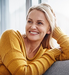 Woman in yellow sweater smiling on couch