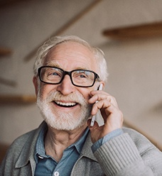 a man smiling with dentures and talking on the phone