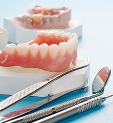 a denture sitting on a mold next to dental instruments