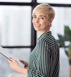 A middle aged woman wearing a striped blouse and showing off her new smile