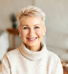 Woman in sweater smiling while sitting in living room