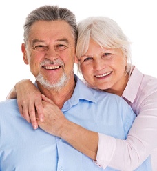 Older couple smiling with woman’s arms around man