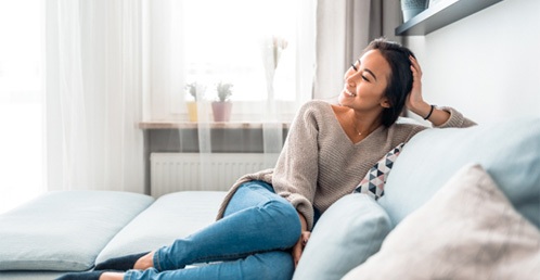 person relaxing on their couch and smiling