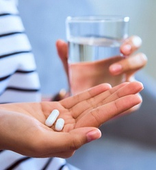 Woman holding painkillers and glass of water