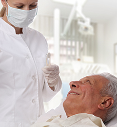 Older man in dental chair smiling at dentist