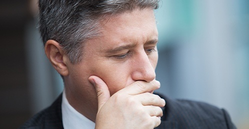 man in a suit covering his mouth