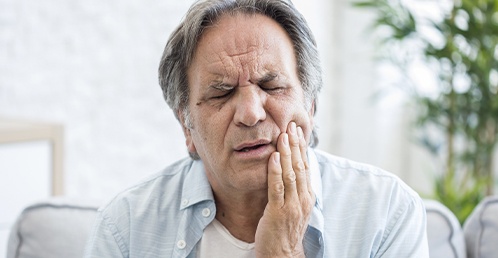 man holding his cheek in pain