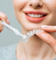 Woman placing teeth whitening gel in tray