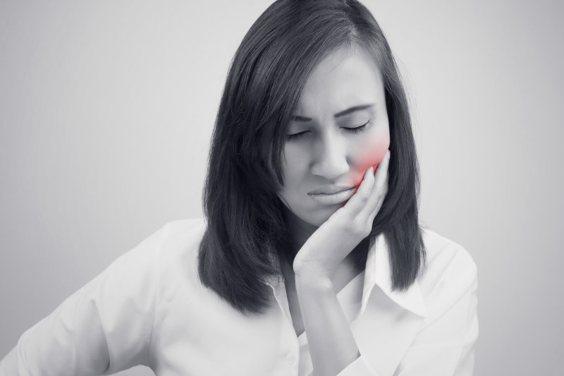 a woman holding her cheek in pain