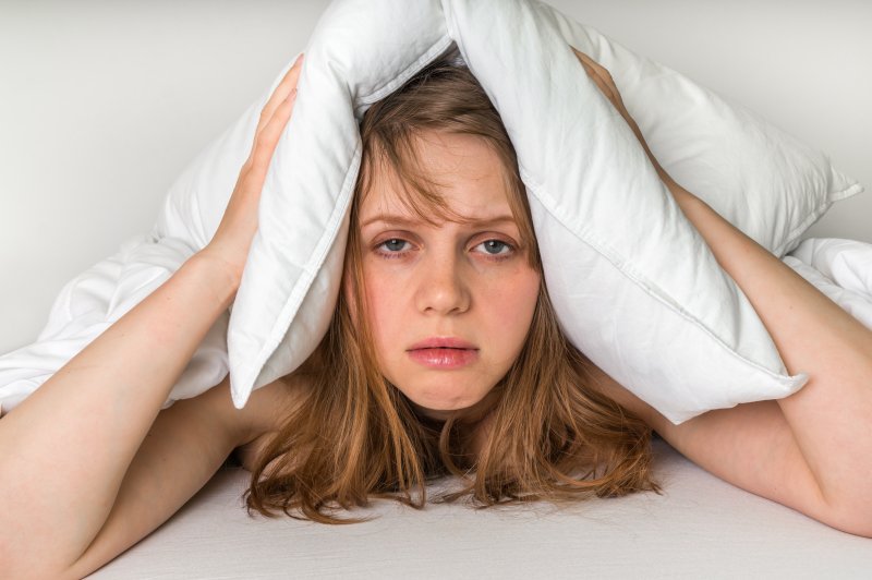 a woman looking very tired with a pillow over her head