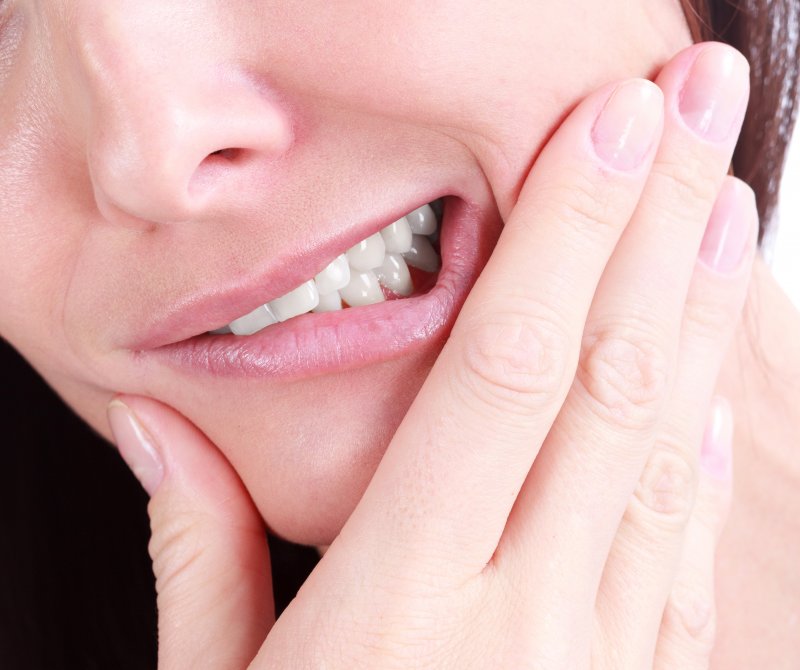 a woman holding her jaw in pain