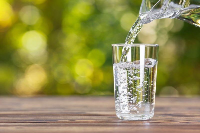 a pitcher full of water being poured into a clear glass