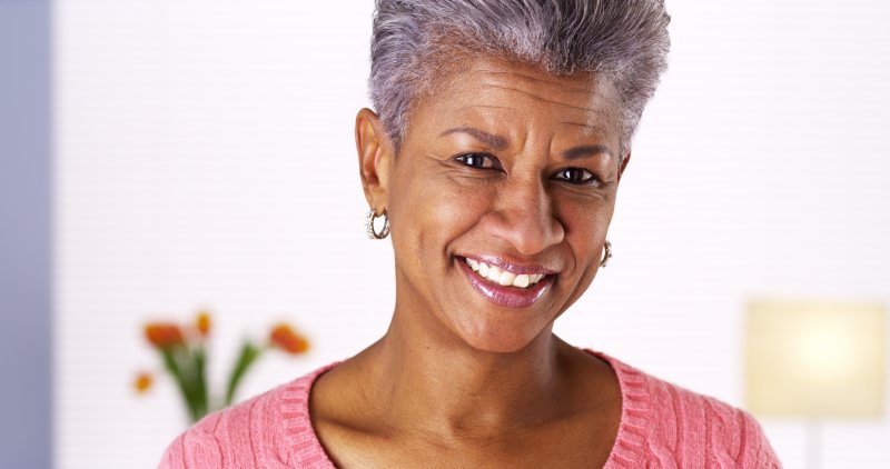 an older woman smiling after receiving treatment by her dentist in Jacksonville