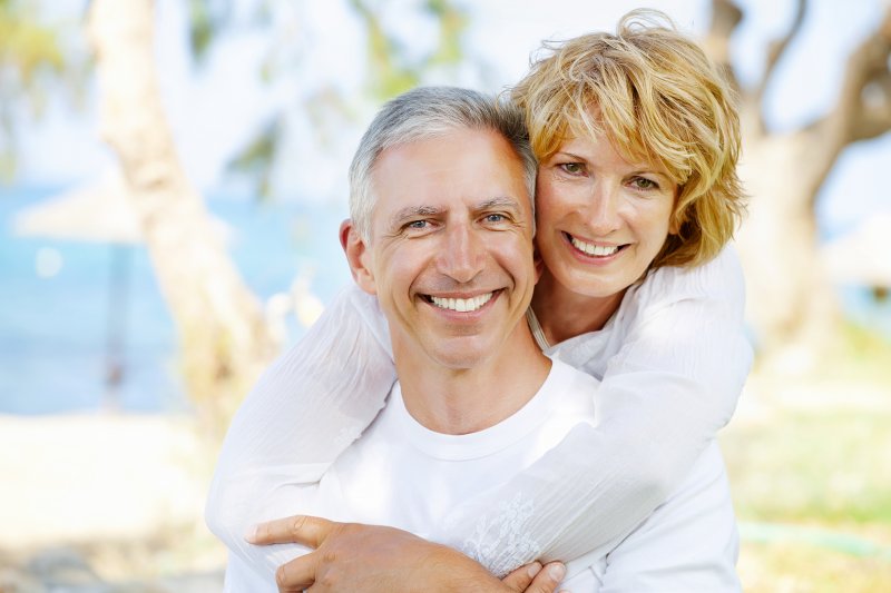 a happy, middle-aged couple hugging and smiling while enjoying the outdoors