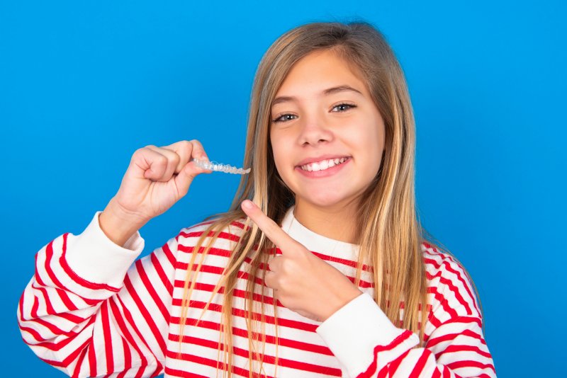 A girl holding up an Invisalign aligner