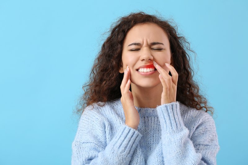 A woman in pain because she needs an emergency dentist