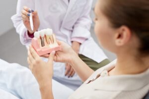 Dentist showing patient a model of dental implant.