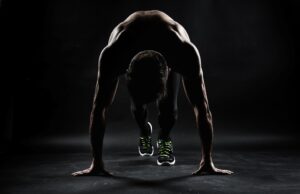 Darkly lit image of runner in starting stance